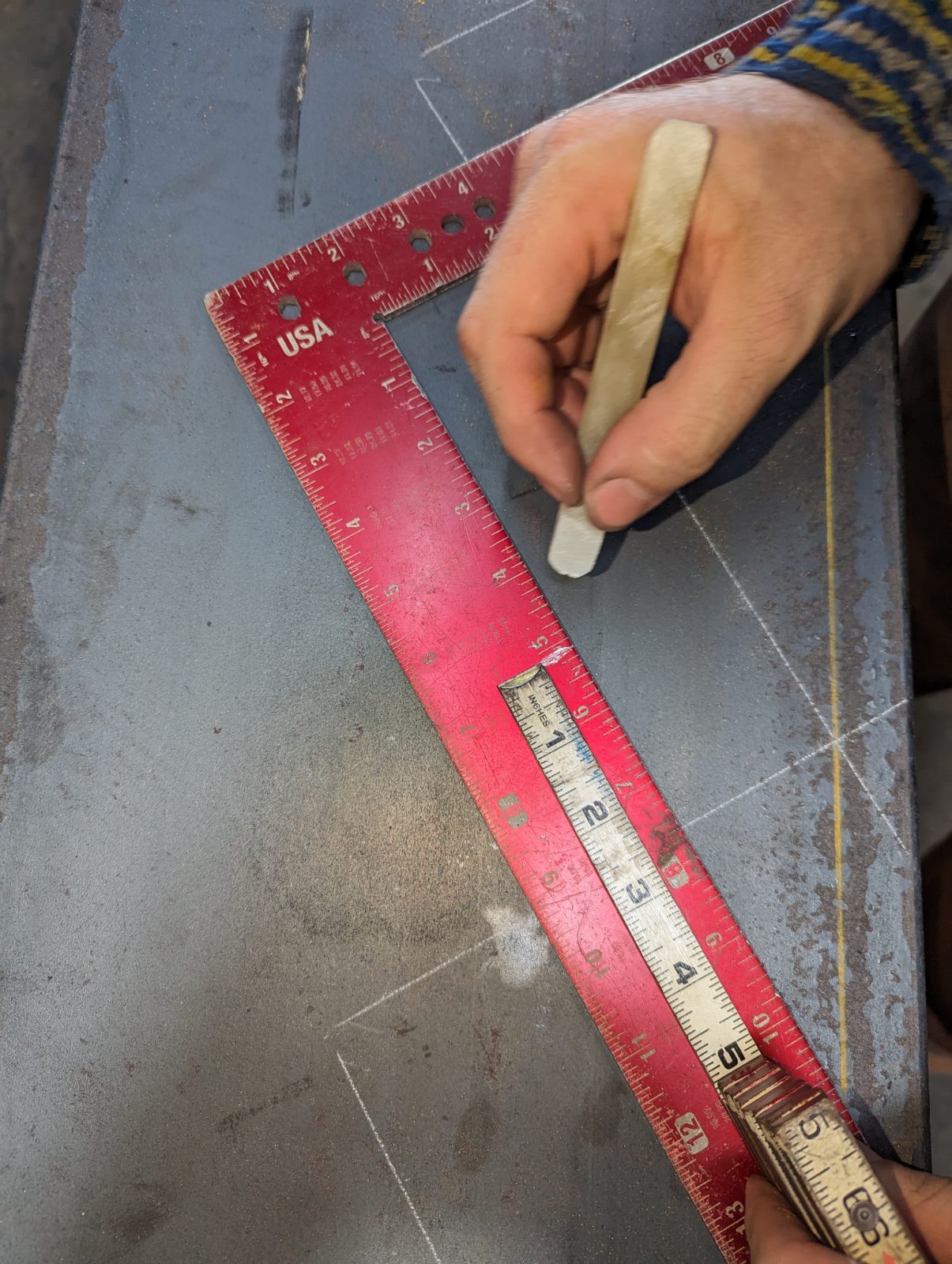 Fabricated steel beams laid out on the shop floor with piece marks